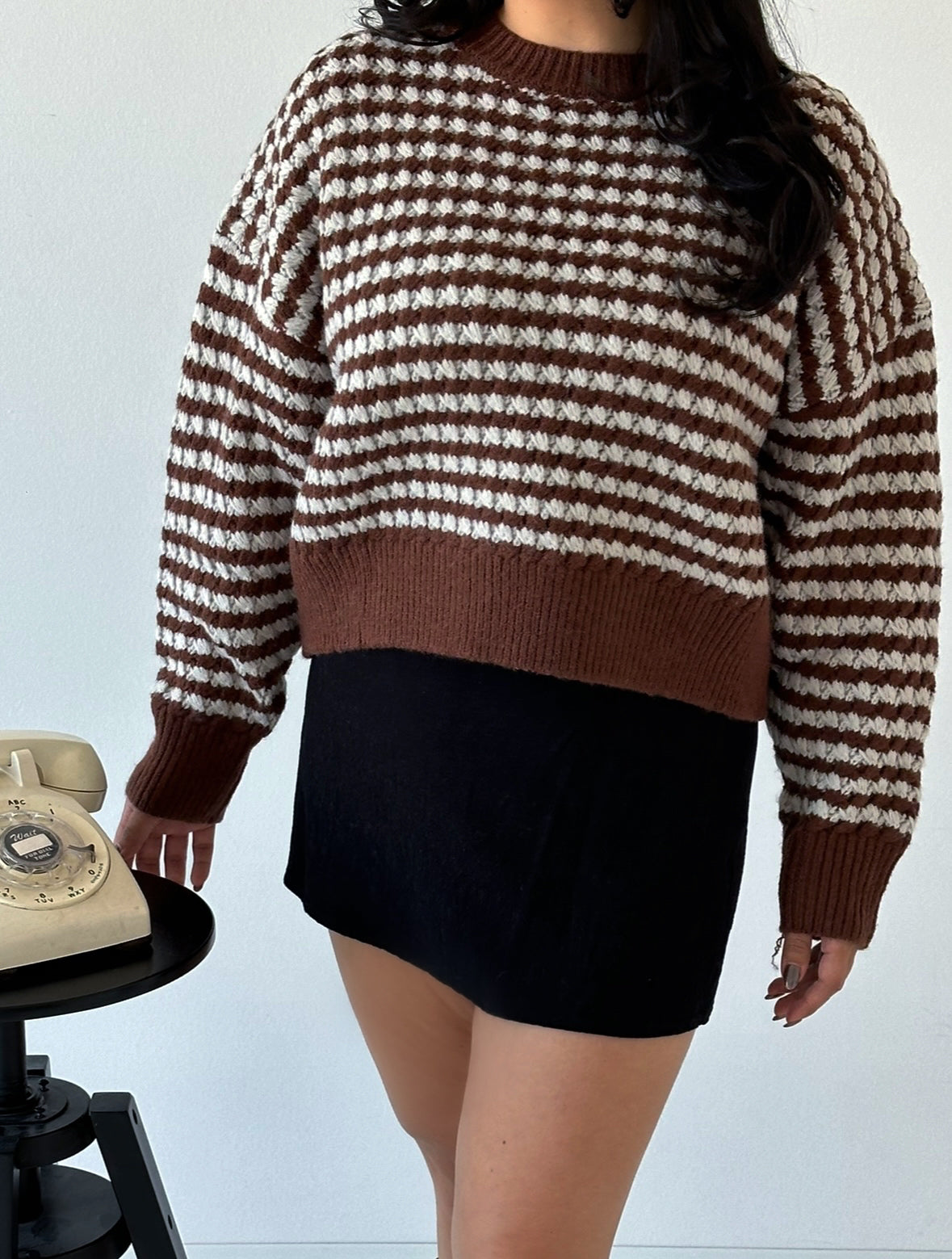 Picture features a brown sweater with light blue stripes on a model wearing a black mini skirt and brown moto knee high boots.