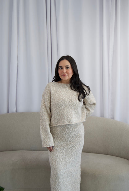 Picture features a two piece boucle material sweater and midi skirt set on a model wearing burgundy boots.