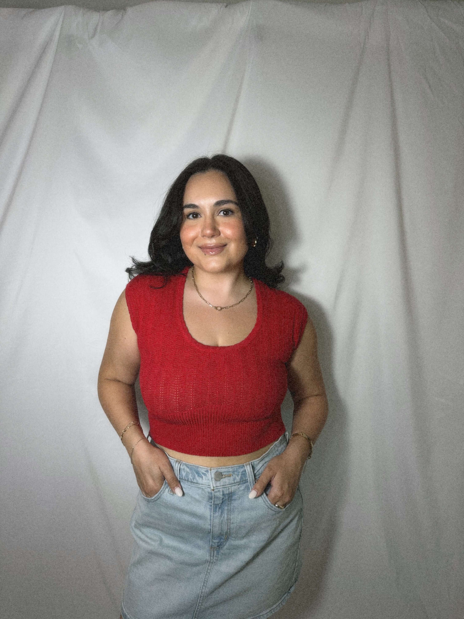 red lightweight sweater blouse with capped sleeves on model in front of blank background.