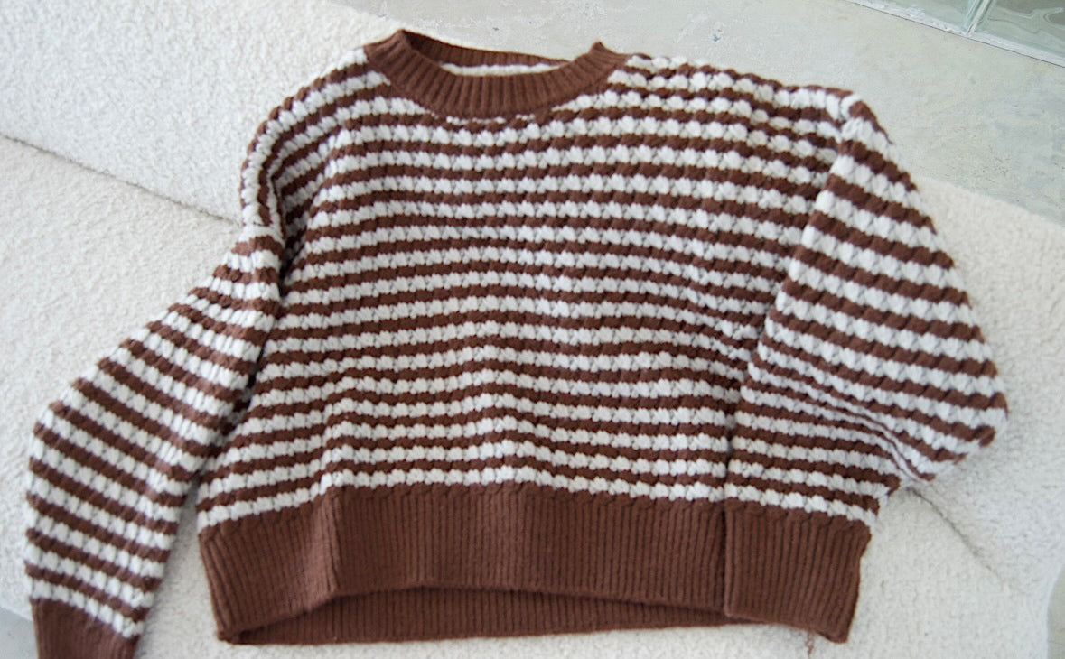 Picture features a brown sweater with light blue stripes on a flat lay.