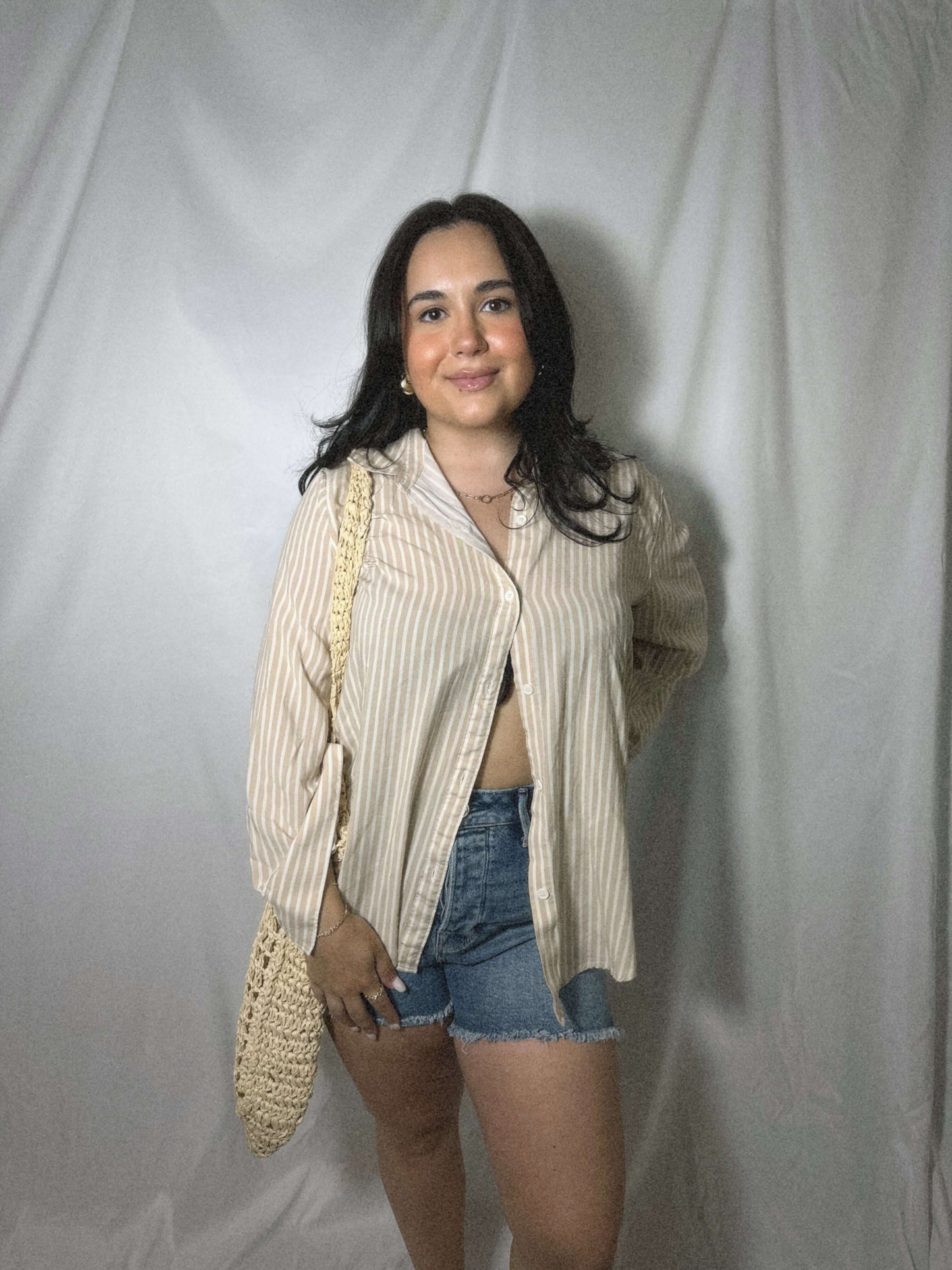 cream and white striped button up top oversized on model in front of white background