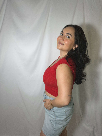 red lightweight sweater blouse with capped sleeves on model in front of blank background.