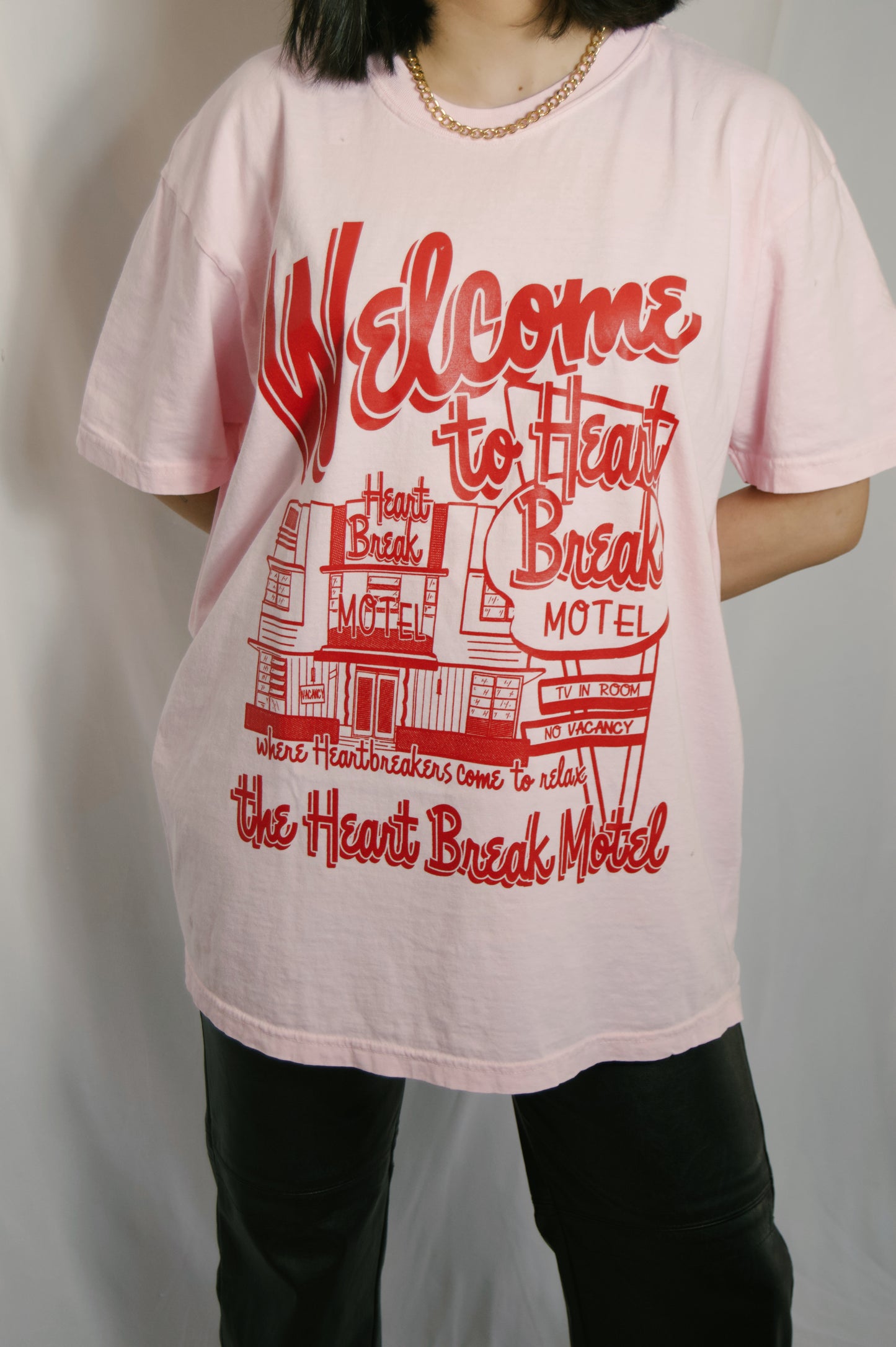 light pink graphic tee with heartbreak motel on it in bright red colors and graphics