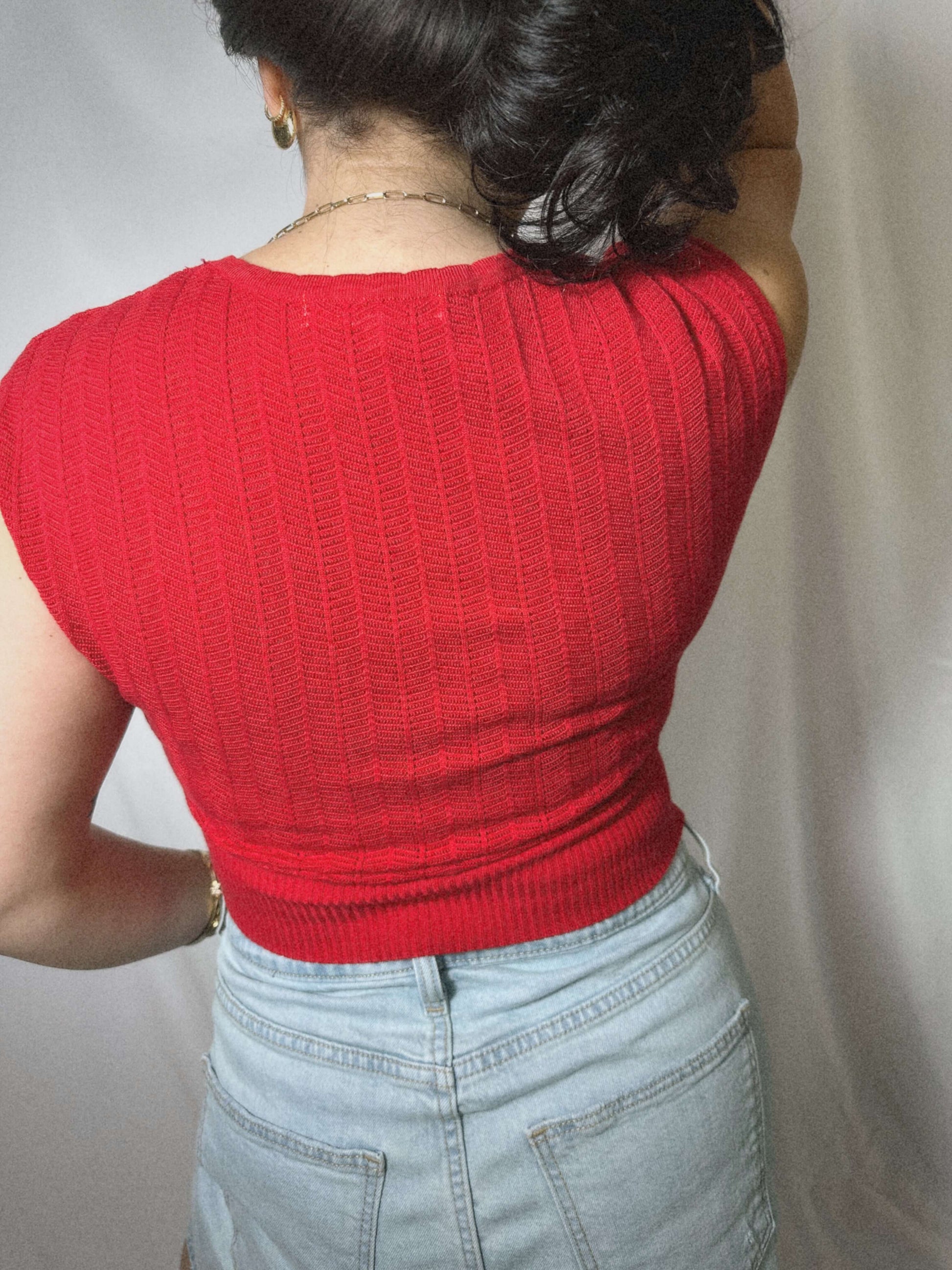 red lightweight sweater blouse with capped sleeves on model in front of blank background.