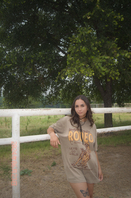 brown oversized graphic tee with yellow colored "not my first rodeo" and horse on it