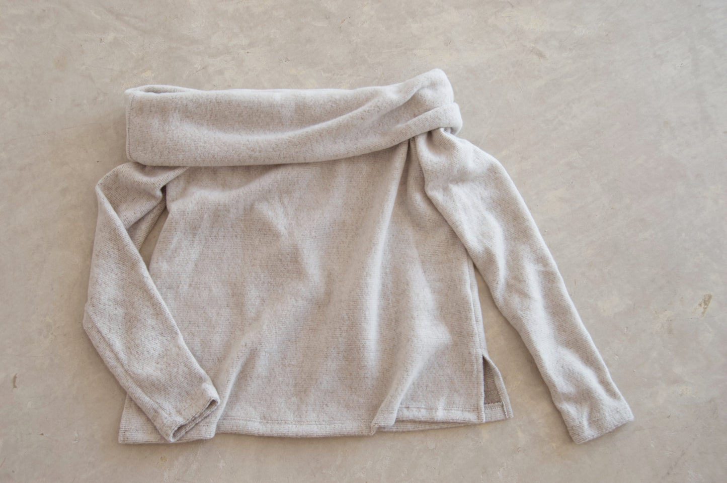 Picture features a light grey off the shoulder sweater on a flat lay.