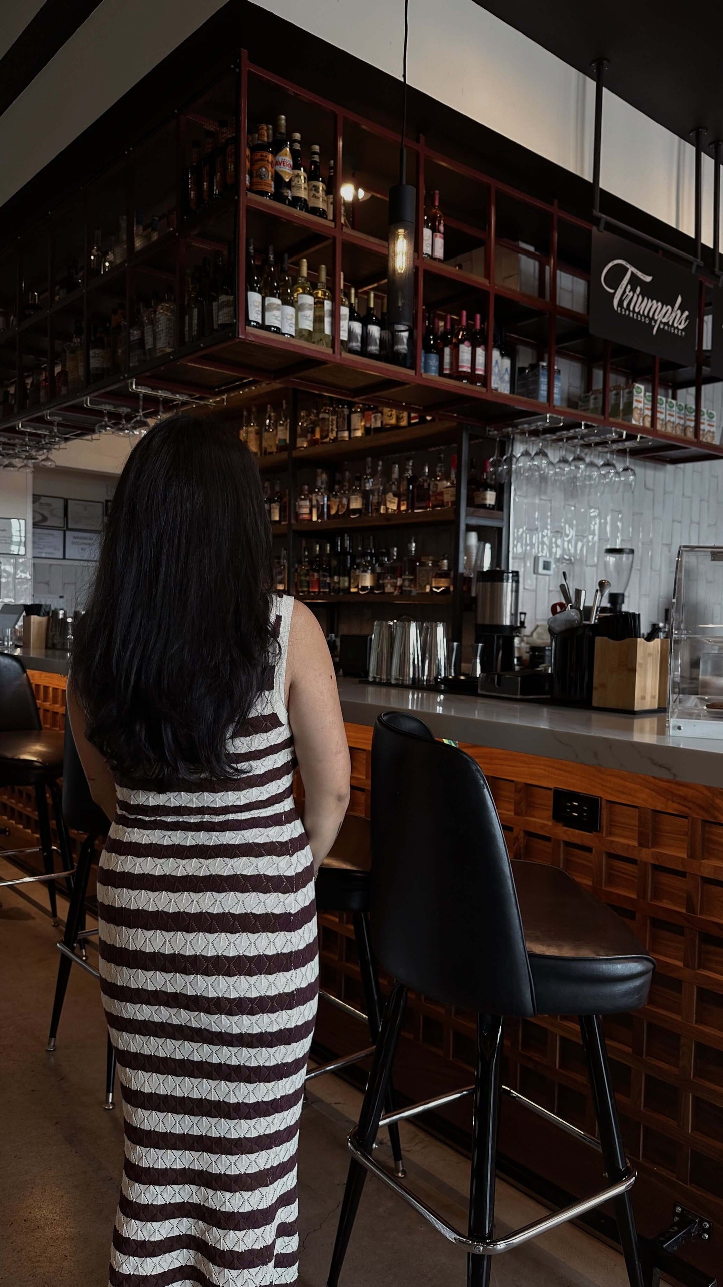 brown and white striped knit maxi dress on model posing with coffee and purse