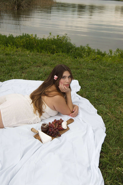 strapless white mini dress with eyelet pattern, tie sides, tie on the front. on model in front of lake.