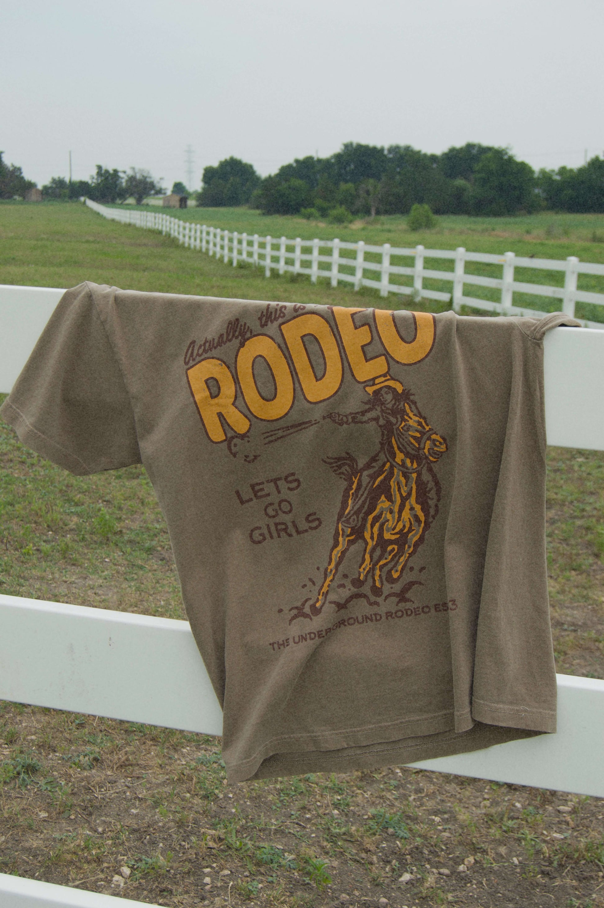 brown oversized graphic tee with yellow colored "not my first rodeo" and horse on it